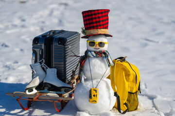Snowman with suitcase ready for holiday trip. Winter vacation starts with snowman. Christmas...