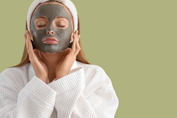 Young woman with applied facial mask on green background, closeup