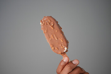 Holding a chocolate ice cream bar with nuts in hand
