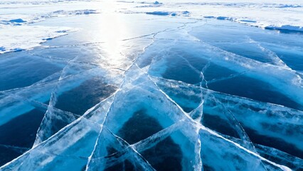 Frozen lake surface with cracked ice patterns reflecting sunlight