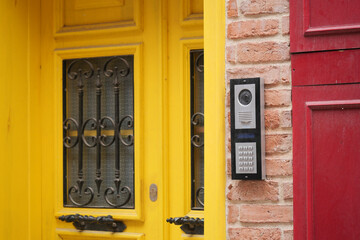 Modern door entry system at a yellow door in a neighborhood