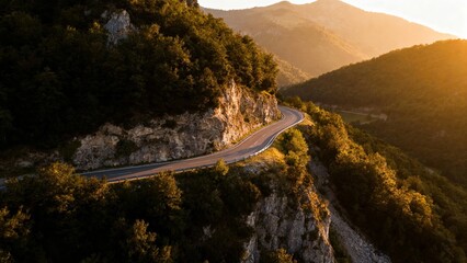 Winding mountain road at sunset with lush greenery and rocky cliffs