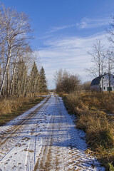 Snow on a dirt road with a Barn at the side
