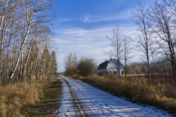 Snow on a dirt road with a Barn at the side