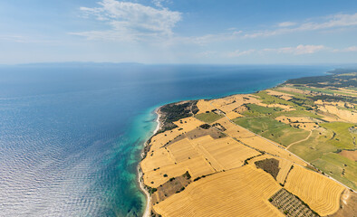Seddulbahir, Turkey. Wide aerial panorama of Teke Cape landscape with fields, forest and coastline, view to Gokceada Island on horizon in haze. Aerial view