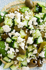 healthy nourish bowl with avocado, jalapeno, feta, green olives and cucumber on hummus