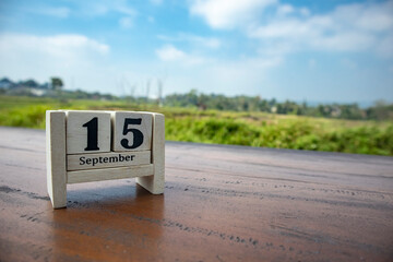 Wooden cube calendar for 15th September place on a table in a sunny day background	
