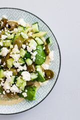 healthy nourish bowl with avocado, jalapeno, feta, green olives and cucumber on hummus