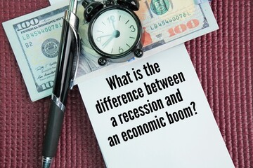 Paper money, bell clock, pen and paper with question words What is the difference between a recession and an economic boom?