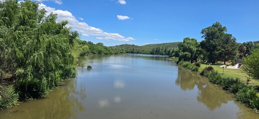 Still river flowing under a bright blue sky.