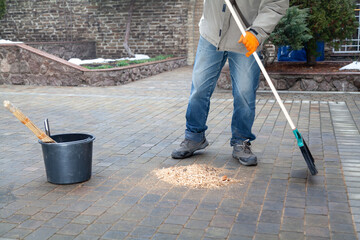 Man sweeping sawdust in yard