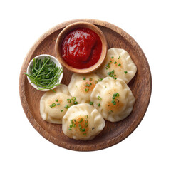 Pierogi on wood plate with chives, sauce, dark background