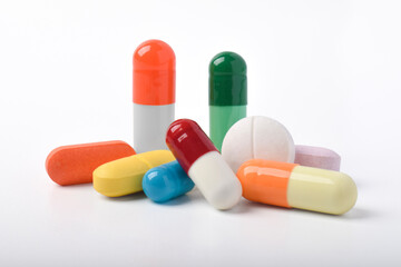 Various colorful pills and capsules on white background, various medicines, vitamins and supplements in healthcare and pharmacy concept.