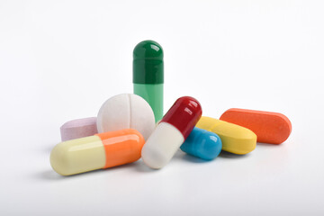 Various colorful pills and capsules on white background, various medicines, vitamins and supplements in healthcare and pharmacy concept.