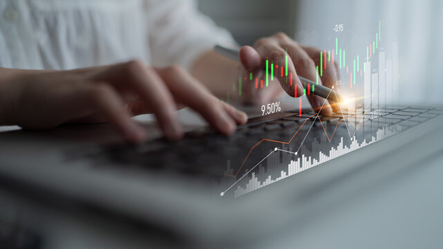 A business professional uses a laptop to analyze financial data and trading charts, representing modern strategies in investment and market analysis. Scalp - Powered by Adobe