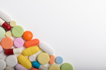 Various colorful pills and capsules form a frame, isolated on a white background, copy space for text. Medical concept.