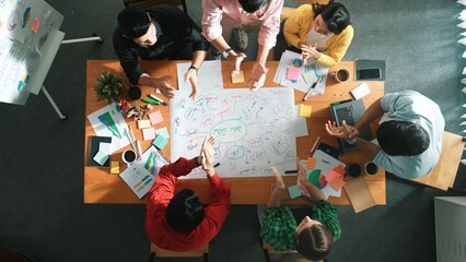 Group of business people writing and making mind map to brainstorming marketing idea at meeting. Top aerial view of investors sharing plan or strategy by using sticky notes and marker. Convocation.