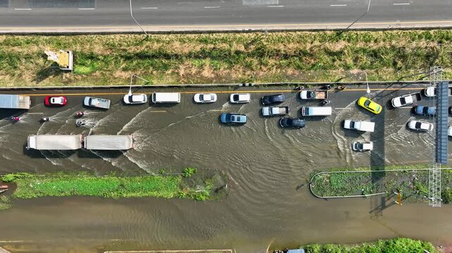 An aerial drone shot shows deep floodwaters stalling traffic, revealing gaps in drainage systems, climate adaptation, disaster response, infrastructure durability, and long-term urban resilience.
