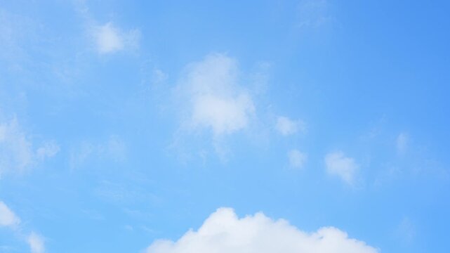A blue sky timelapse featuring soft cirrus and scattered cumulus clouds drifting gently across a bright, clear backdrop, highlighting serene daylight movement and subtle cloud textures. Time lapse.
