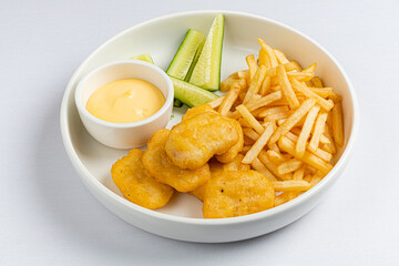 A tempting plate of crunchy nuggets, golden fries, and refreshing cucumbers await hungry diners