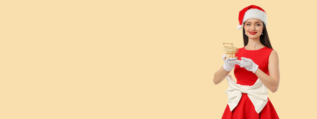 Woman wearing a red dress and Santa hat holds a small cart