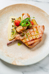 A perfectly grilled pork chop rests beside silky mashed potatoes and colorful side vegetables