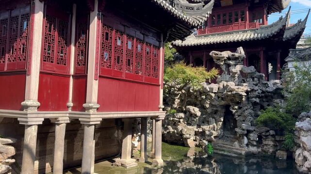 A classic wooden red pavilion, Yu Garden overlooks sun-drenched rocks surrounded by lush greenery.