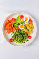 A vibrant salad featuring smoked salmon, creamy avocado, cherry tomatoes, and perfectly boiled eggs
