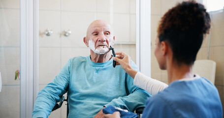 Elderly man, nurse and shaving in bathroom with wheelchair, product and foam for grooming in home....