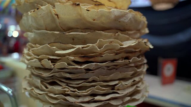 Tlayudas stacked on market counter showing crisp texture and traditional Oaxacan street food, detailed closeup
