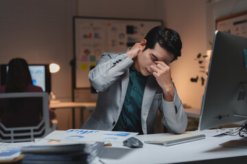Stressed young businessman feeling tired working late at office