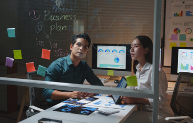 Business colleagues analyzing data discussing marketing strategy at night