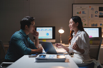 Asian business colleagues discussing financial data together at night