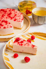 Creamy cheesecake with raspberry topping, paired with herbal tea in a cozy ambiance