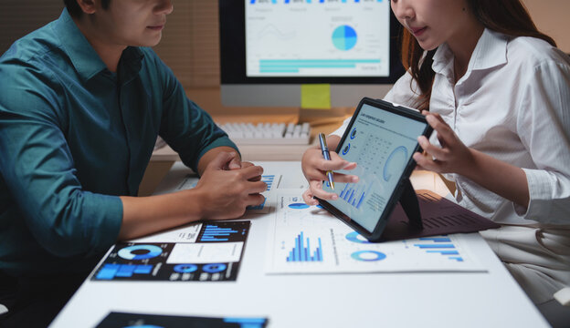 Business colleagues analyzing financial dashboard data on tablet - Powered by Adobe