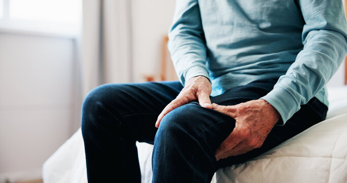 Hands, senior man and leg pain at house from arthritis, parkinson and muscle inflammation. Closeup, elderly person and discomfort of pinched nerve, fibromyalgia and joint cramps from poor circulation