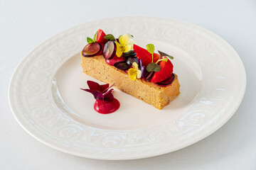 A crafted dessert features creamy richness topped with vibrant fruits and flowers