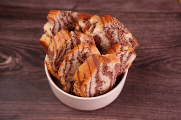 close-up view of marble cake slices arranged neatly in a white bowl on a textured wooden surface, showcasing a delightful swirl pattern of chocolate and vanilla, leisure, classic, oven, bake