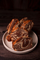 close-up of sliced marble cake on white plate with dark countertop setting, highlighting textured swirls and rich brown tones for a cozy, homely atmosphere, browns, gourmet, served, decor, elegant