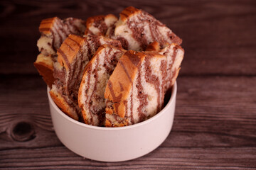 close-up of marbled chocolate and vanilla cake slices in a white bowl on wooden surface creating a cozy and warm atmosphere with rich brown and creamy tones, creams, browns, light, portion, slice