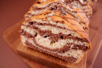 close-up of sliced marble cake with rich swirls of vanilla and chocolate on a wooden cutting board with soft focus background, softness, brownie, yummy, flavorful, crumb, artisanal, traditional
