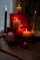 warm ambient glow of candles atop red gift boxes with soft bokeh in cozy indoor setting, evoking holiday spirit and tranquility with flickering flames, quiet, elements, arrangement, decorative