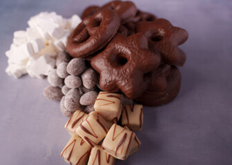 a tempting assortment of chocolate-covered treats with marshmallows and frosted nuts, artfully arranged on a light neutral background for a festive indulgence, elegant, gift, combination, gather