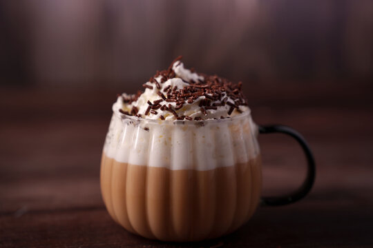 warm coffee beverage topped with whipped cream and chocolate sprinkles in a glass cup with a dark background, creating a cozy and inviting atmosphere, velvety, rich, satisfying, joyful, gourmet - Powered by Adobe