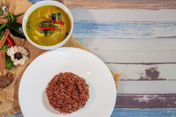 Authentic Thai Green Curry served with brown rice on a rustic wooden table background, delicious Asian cuisine.