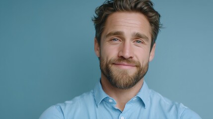Handsome confident man in blue shirt smiling warmly in bright modern workplace