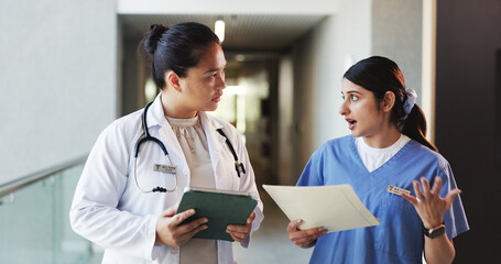 Doctor, tablet and nurse discussion with file in hospital for medical opinion, update or advice. Health team, women and walking in clinic hallway with treatment feedback, surgery schedule or workflow