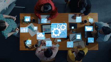 A diverse team engages in a strategic planning meeting, utilizing digital tools and infographics to drive discussions and enhance productivity in a modern workspace. Trope