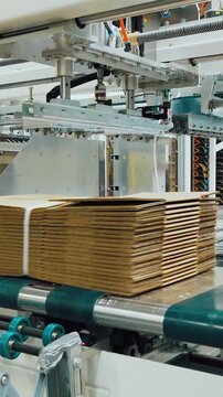 Automated sheet handler. Automated cardboard layering and packing station with conveyor system, Robotic station for stacking and packaging corrugated sheets using conveyor and suction mechanisms