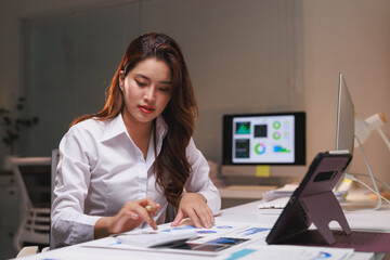 Young businesswoman working overtime analyzing financial data
